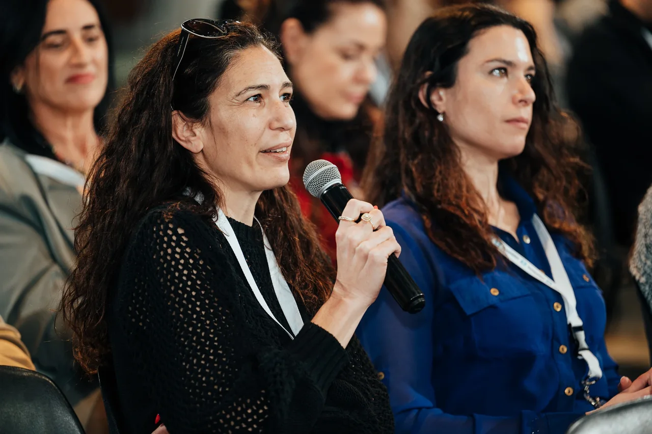 משתתפת מדברת במיקרופון מתוך הקהל — צילום אמנון חורש